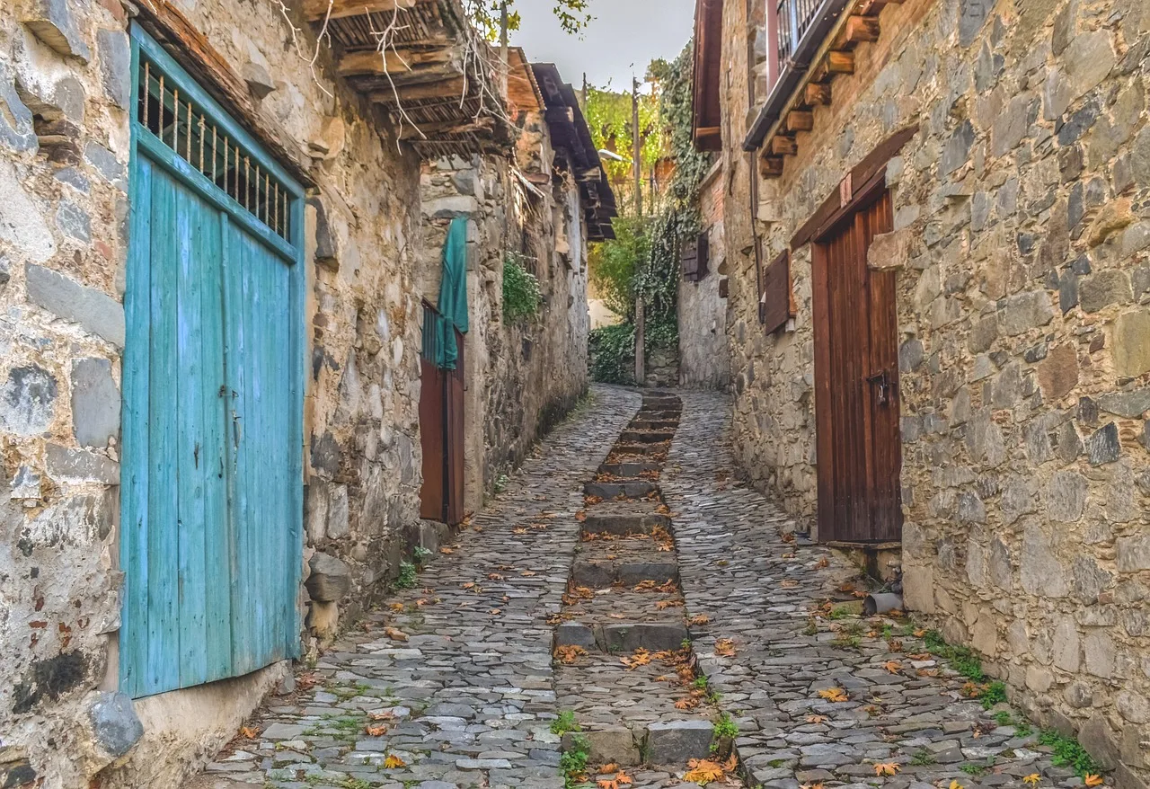 Calle empedrada de un pueblo de montaña, con hojas de otoño en el suelo