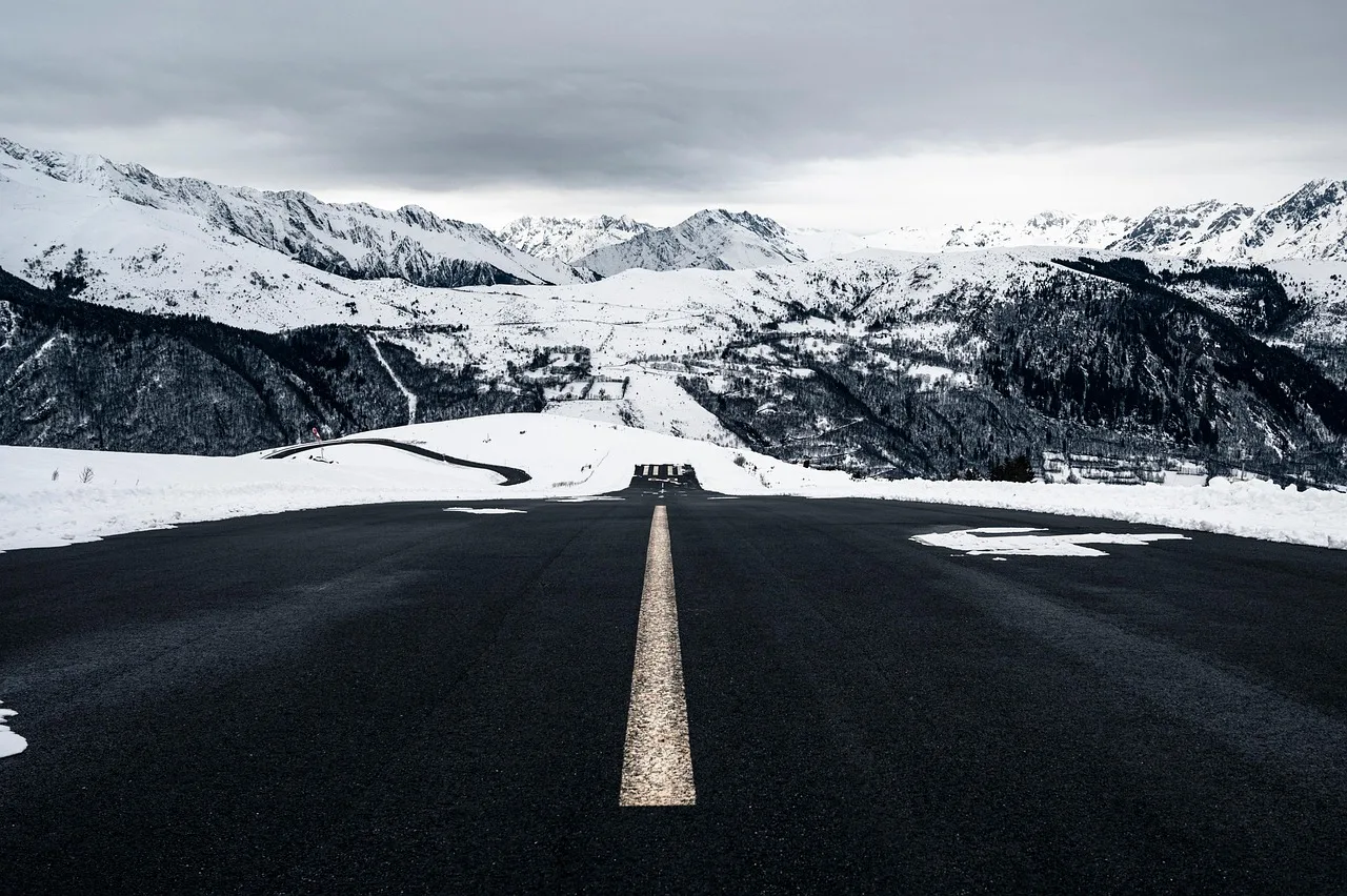 Carretera de montaña despejada entre laderas nevadas