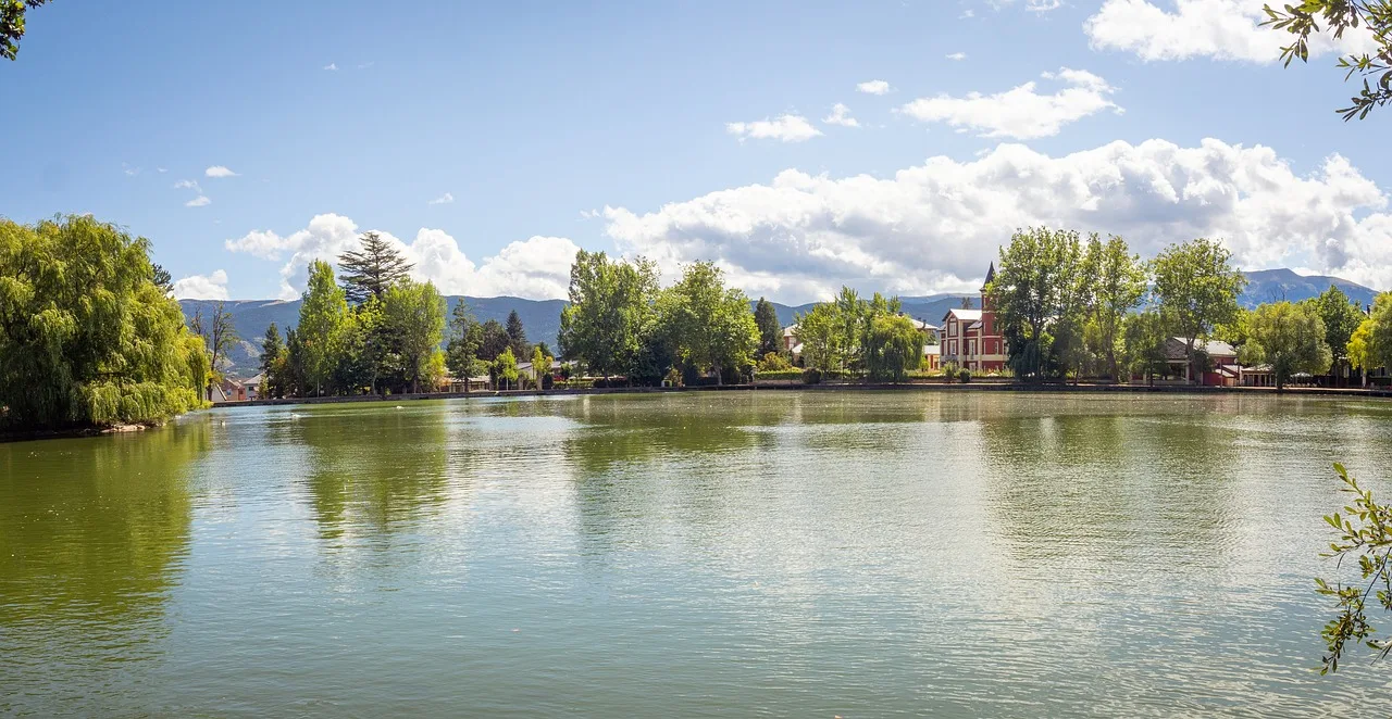 El estany de Puigcerdà en verano, con las casas de la orilla y las montañas al fondo