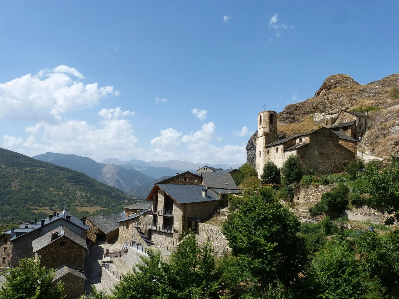 Pueblo de piedra del Pirineo con su campanario románico y las montañas al fondo